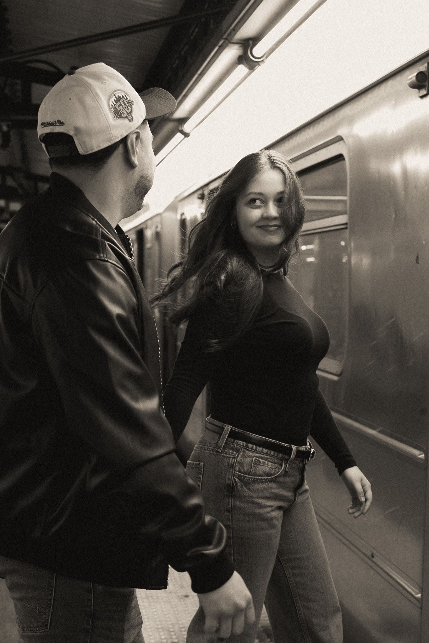 Couple sharing a moment in black and white on subway platform with urban aesthetic.