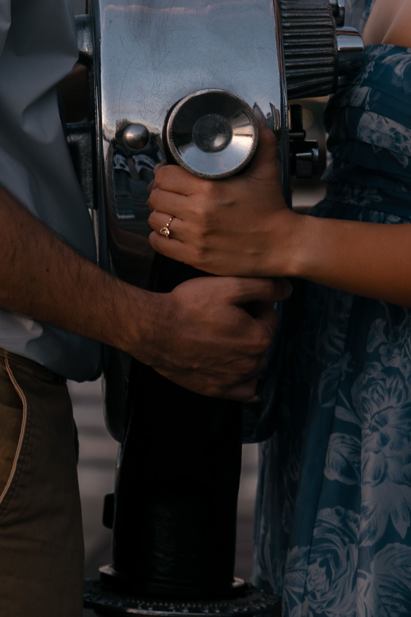 Close-up of hands operating a vintage coin-operated viewfinder telescope.