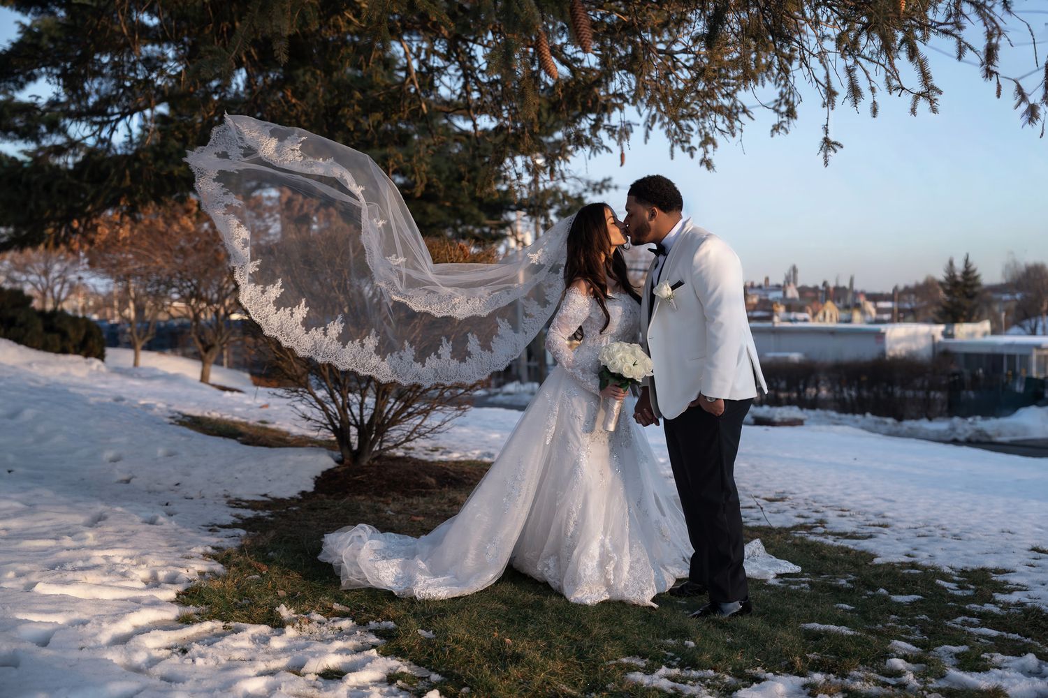 A romantic winter wedding photo session with snow-covered landscape and evergreen trees in the background.