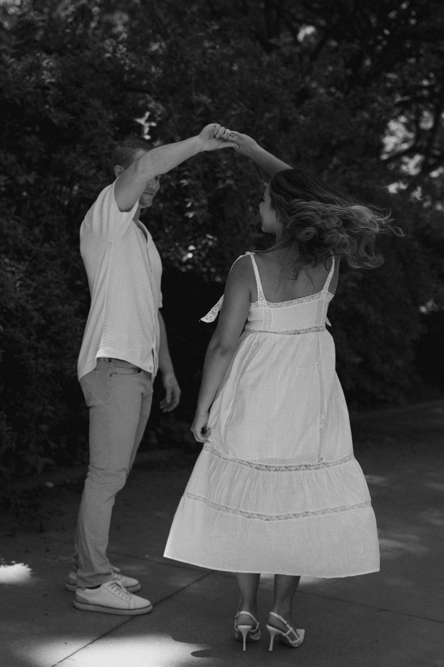 Dancing figures in white clothing moving gracefully on an outdoor patio.