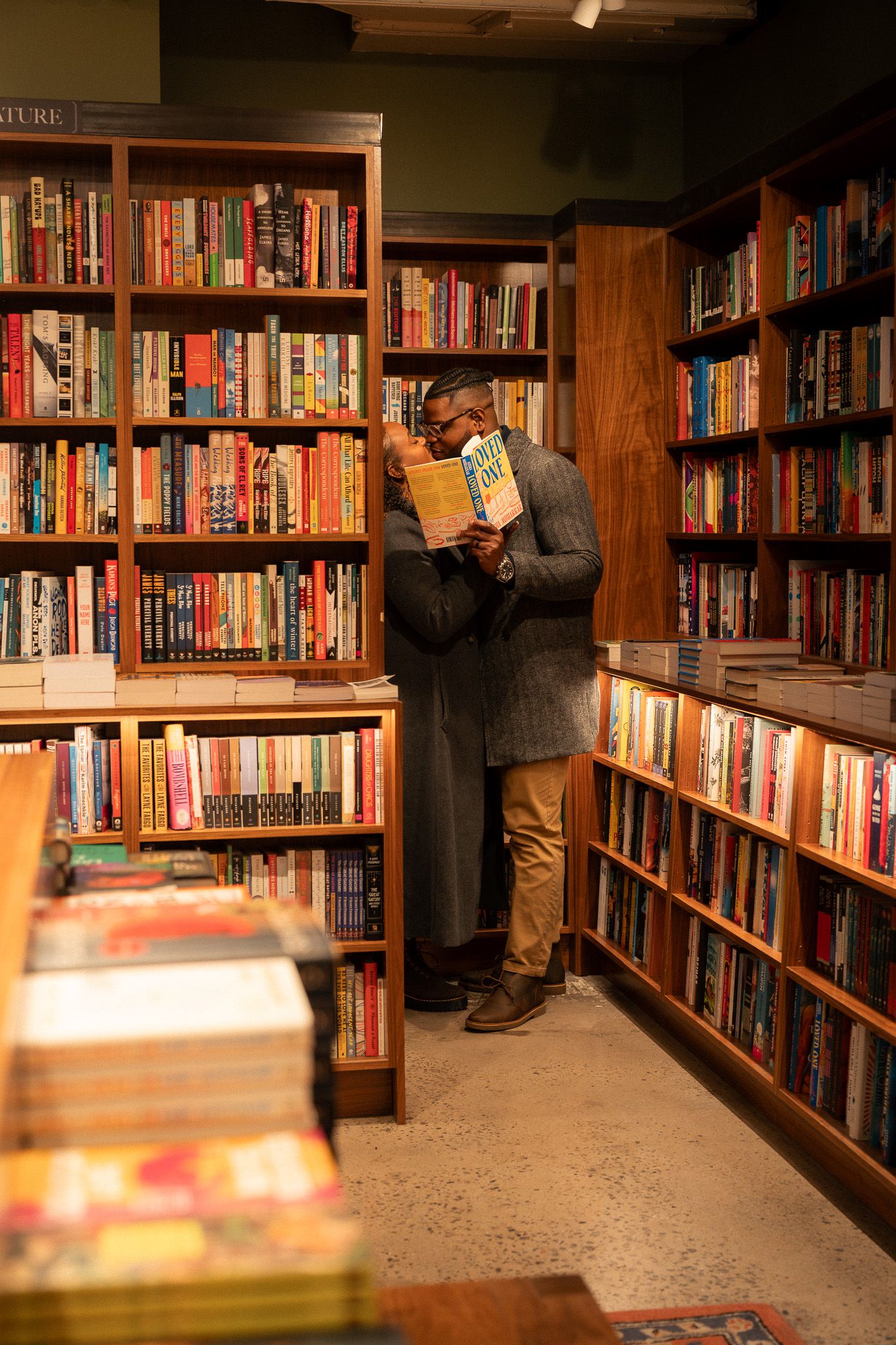 Cozy used bookstore interior with wooden shelves filled with books creating narrow aisles and warm lighting.