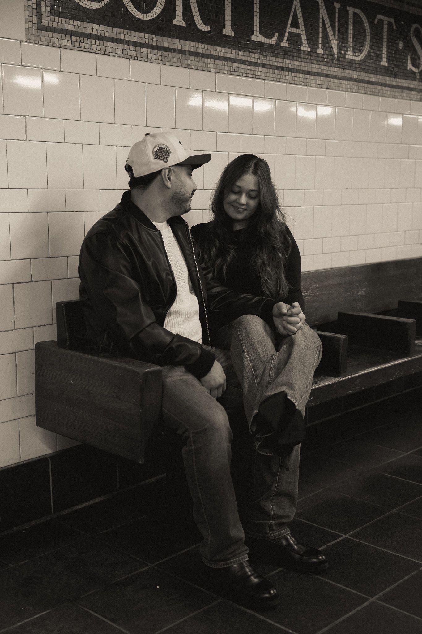 A black and white photo of people sitting on a bench at Cortlandt Street subway station.