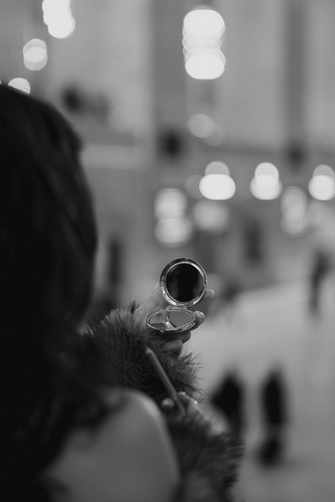 Black and white close-up of a trumpet bell being played with bokeh lights in the background.