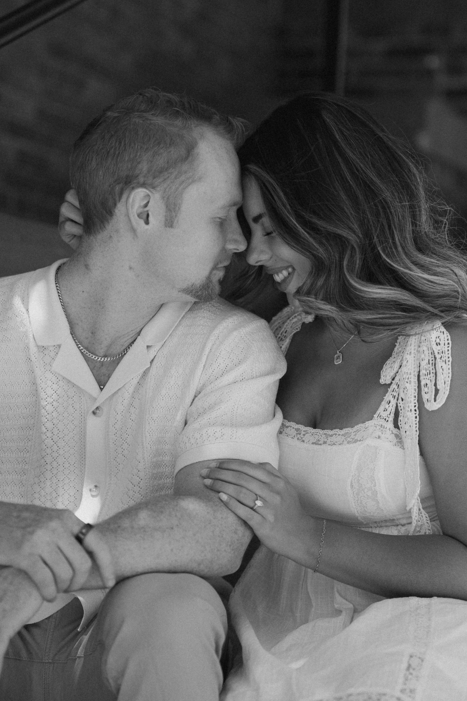 Intimate black and white portrait of a couple in white clothing embracing.