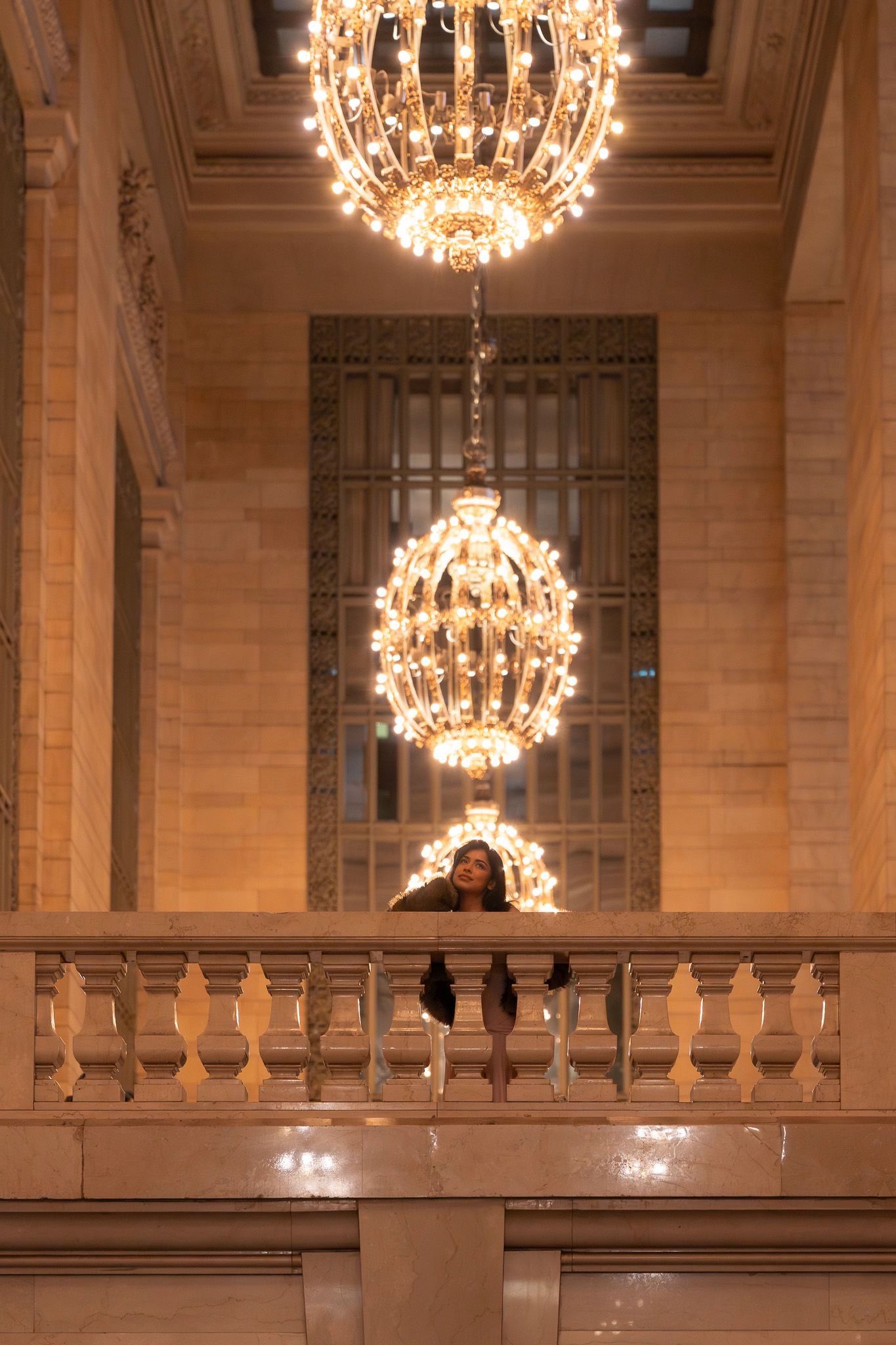 A glamorous evening photoshoot under crystal chandeliers in a grand architectural space.