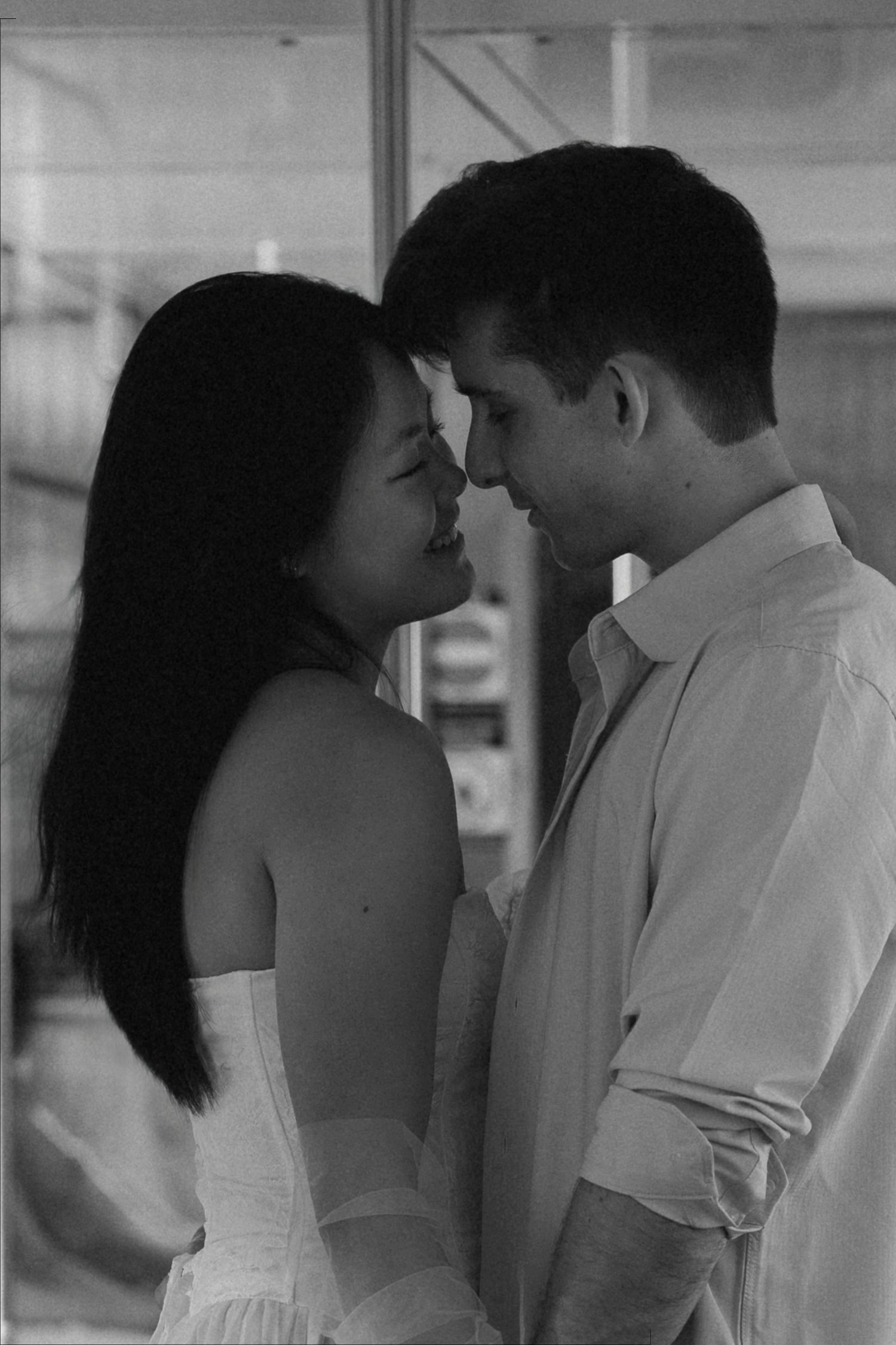 Black and white photo of a romantic couple standing close together, faces nearly touching, sharing an intimate moment.