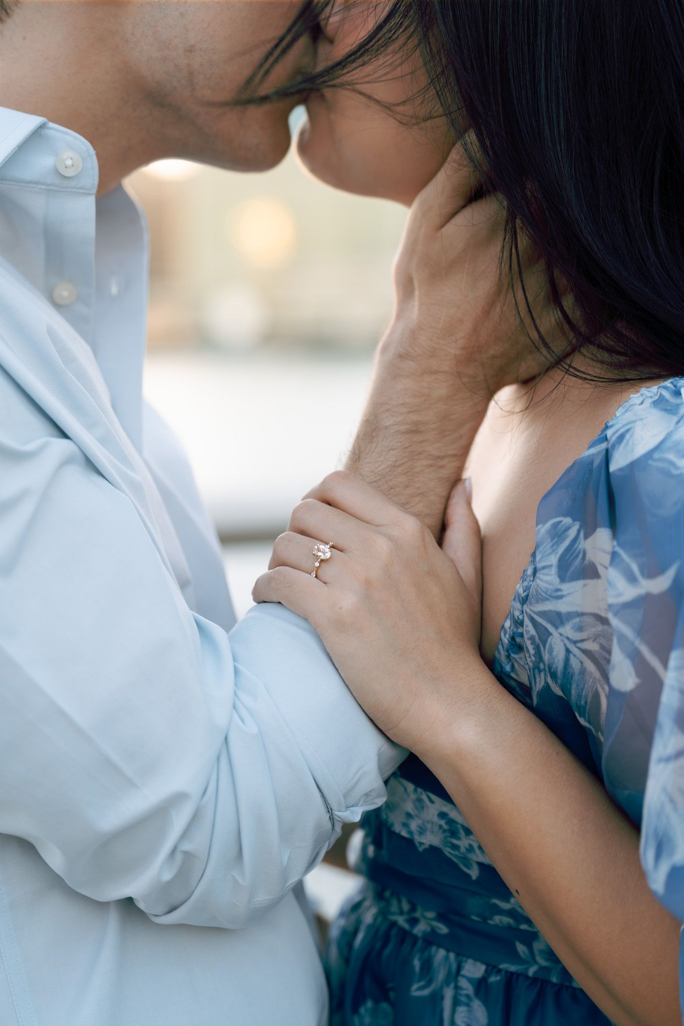 A tender romantic moment captured in close-up showing hands and gentle intimacy at sunset.