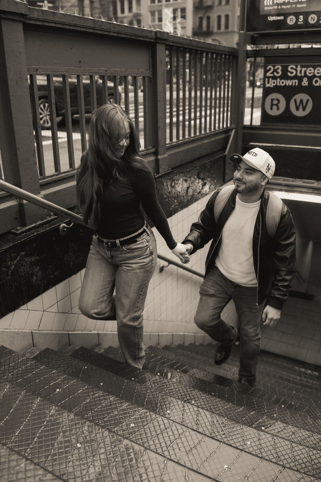 People stand near subway station signage in a vintage-style black and white photograph.