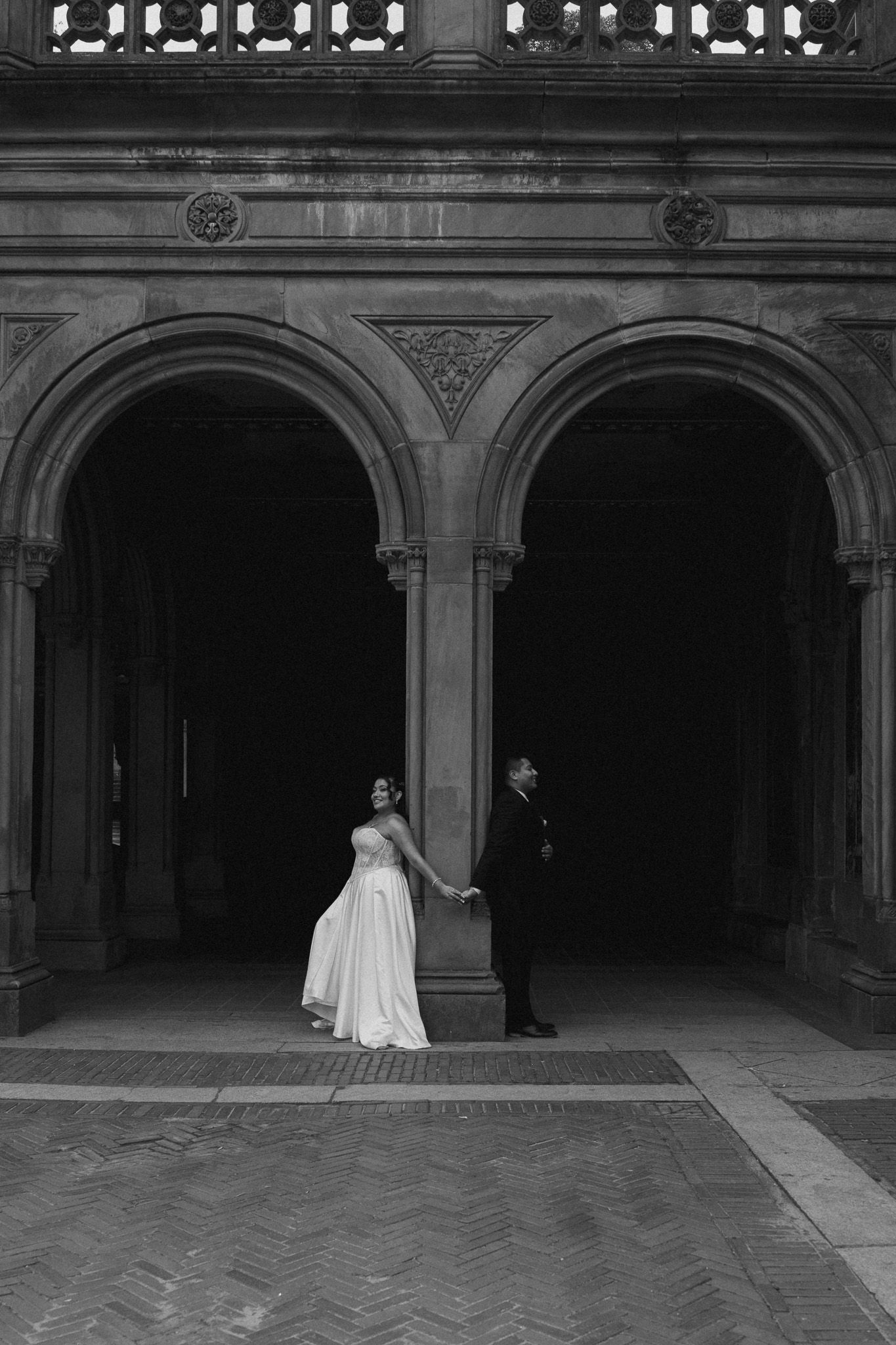 Wedding couple photographed in dramatic black and white under stone archways.