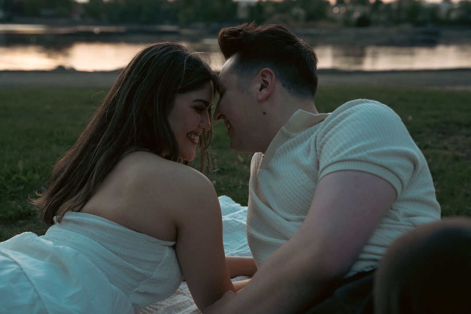 A tender sunset moment between a couple on a blanket outdoors.