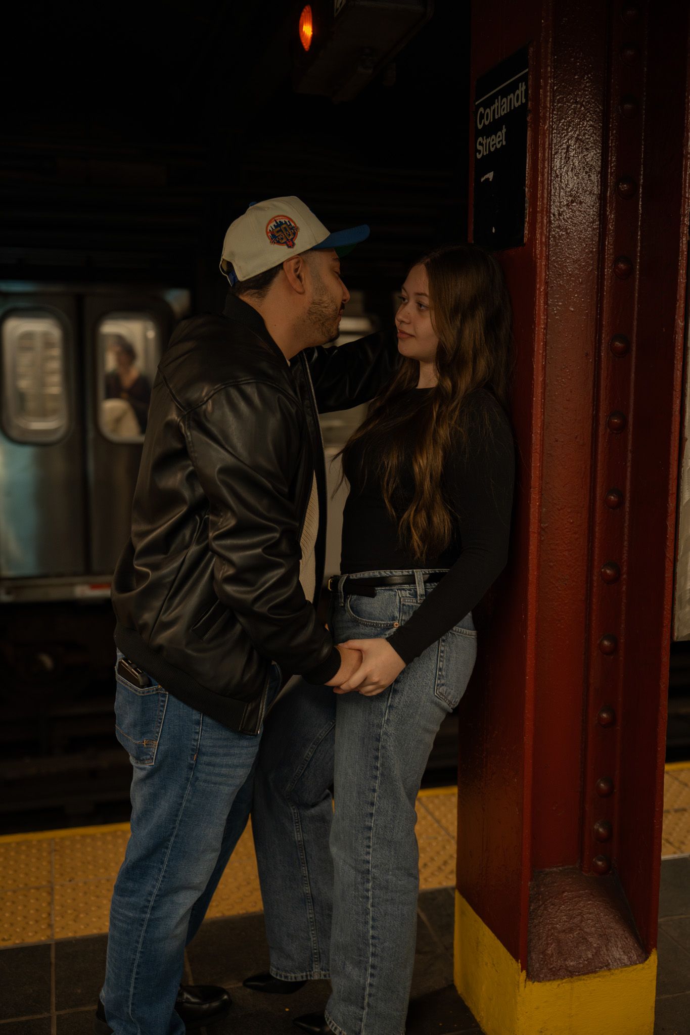 A romantic scene unfolds in a subway station with moody lighting and dark shadows.