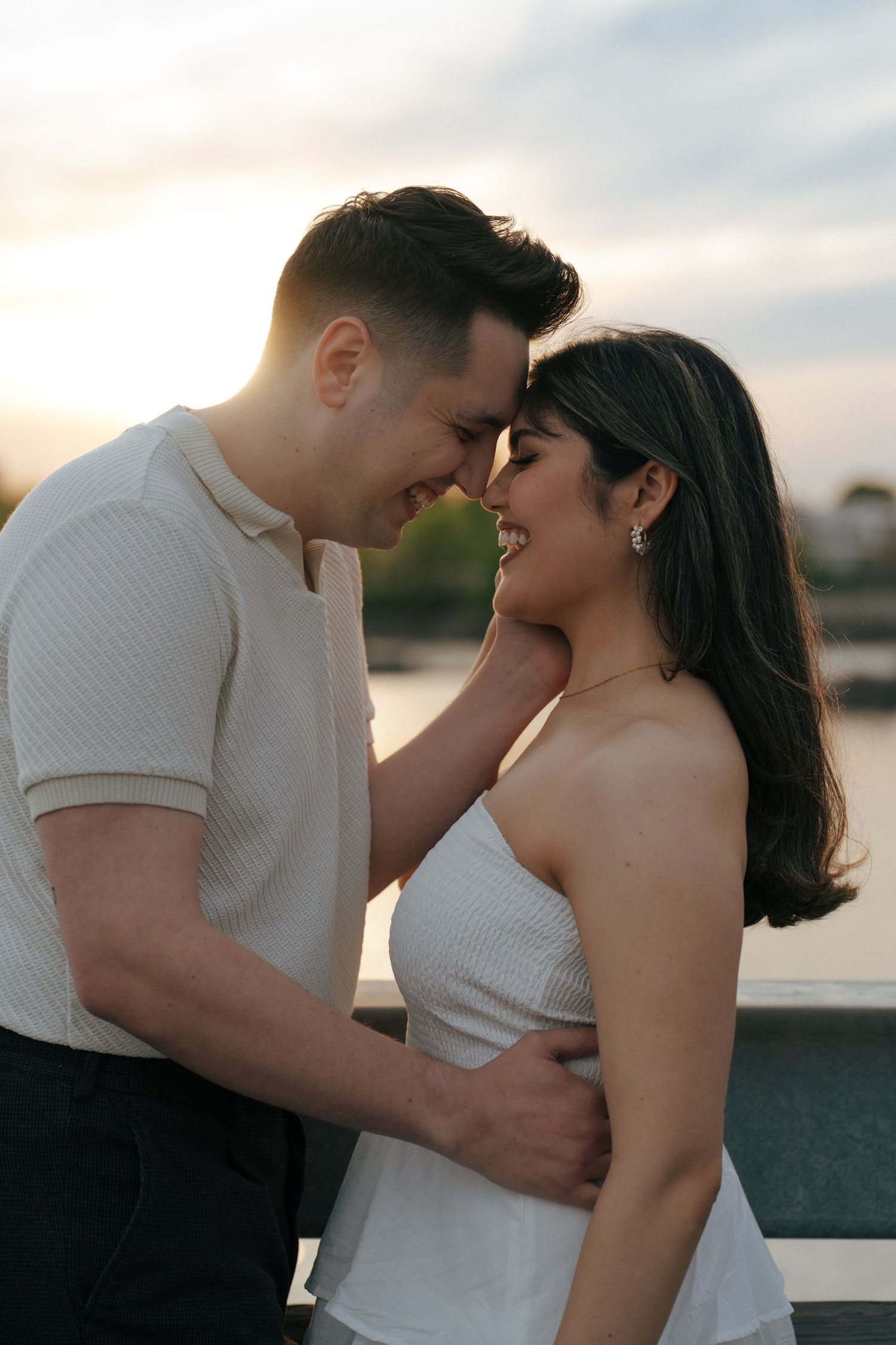 A couple shares an intimate moment at sunset by the waterfront.