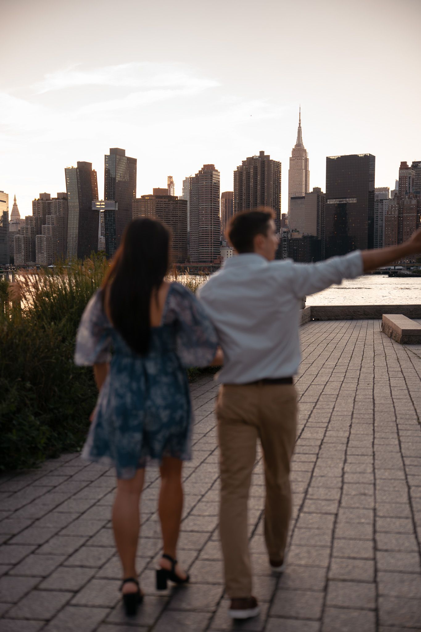 Playful couple dancing against the Manhattan skyline backdrop at dusk.