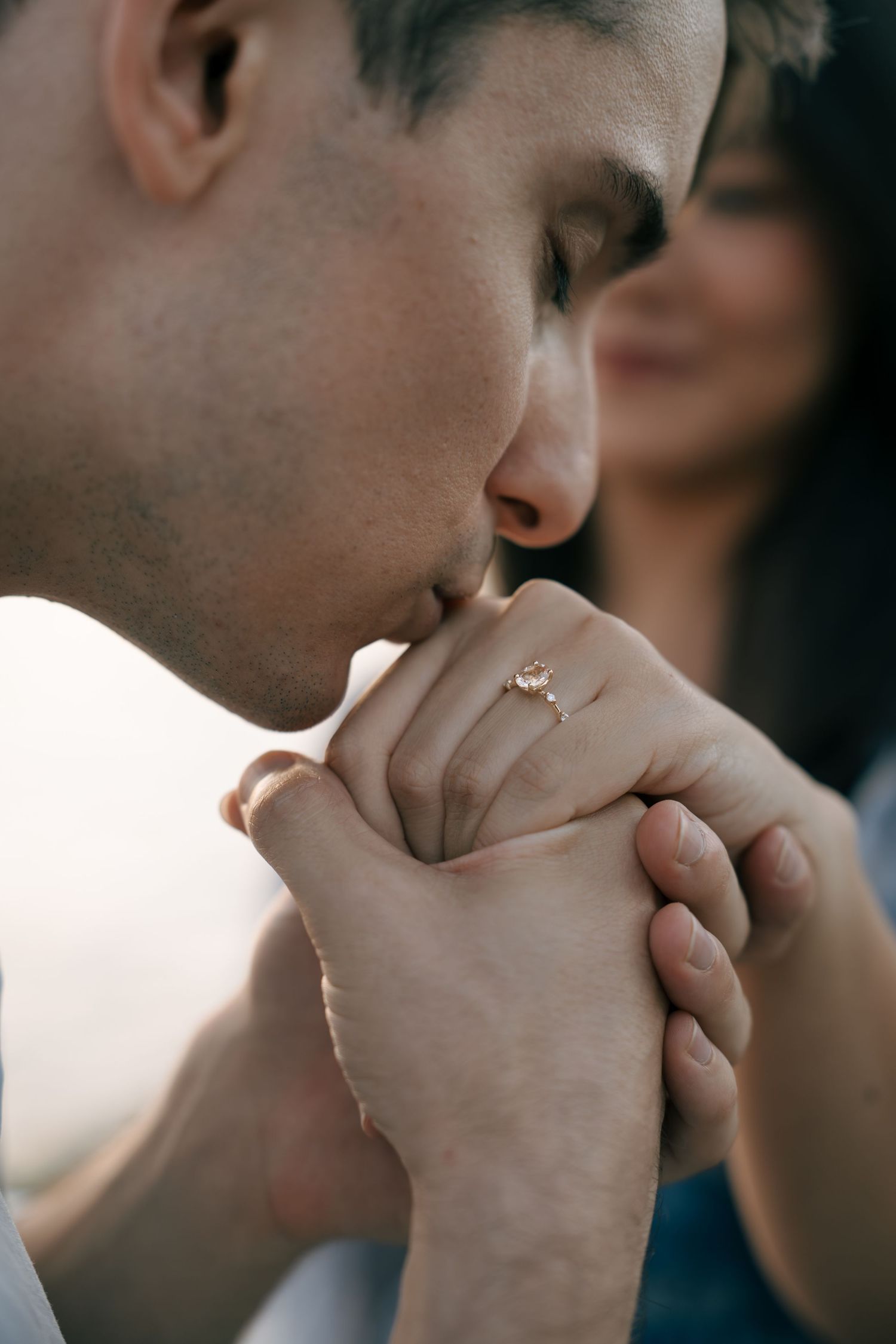 Close-up shot of clasped hands with an engagement ring, showing an intimate romantic moment.