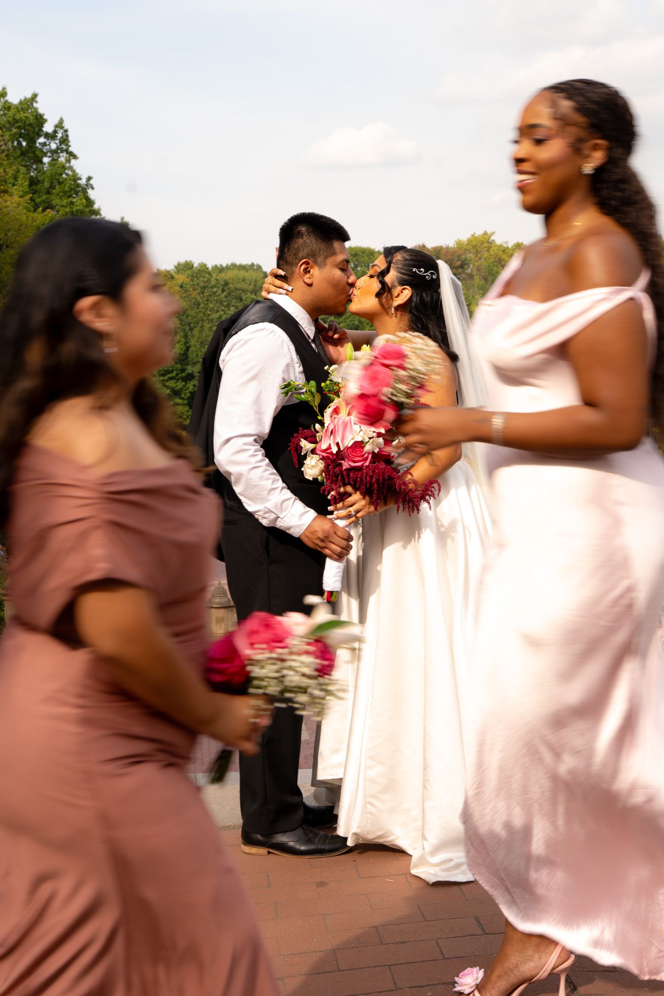 Wedding party members in motion during outdoor ceremony with vibrant pink bouquets.