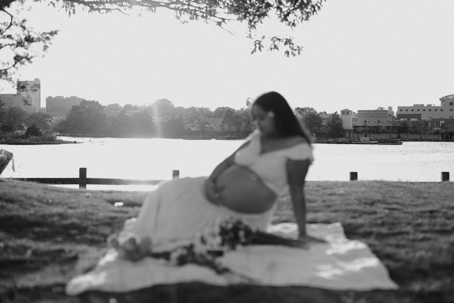 Couple lying on blanket in park with cityscape visible in background.