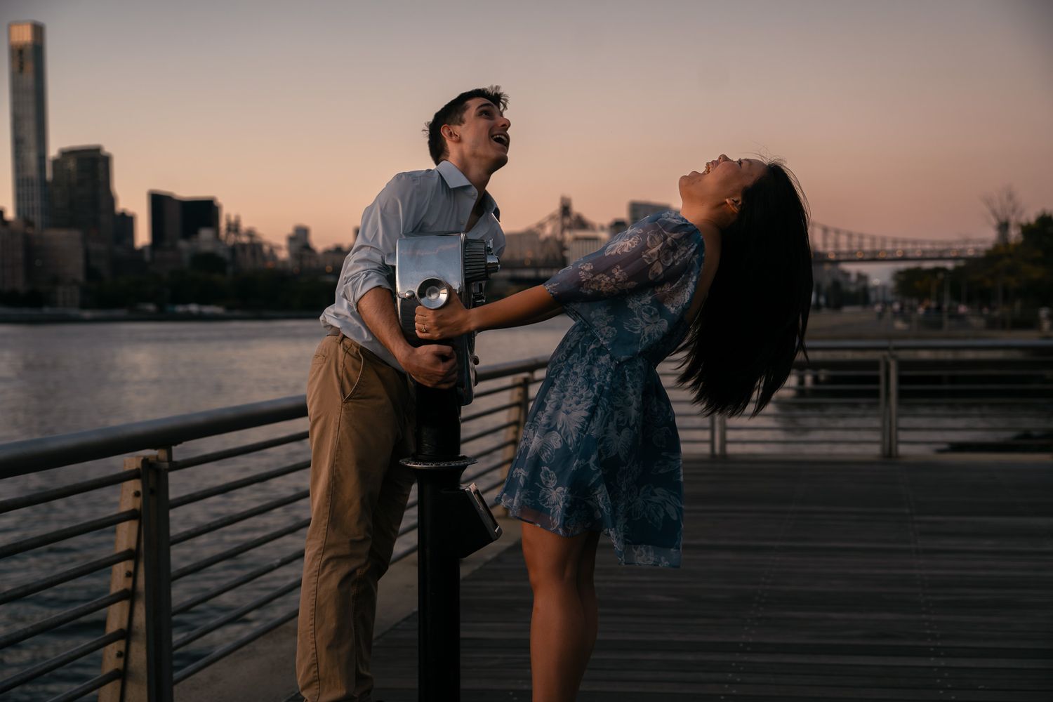 Romantic sunset moment captured on waterfront boardwalk with city views.