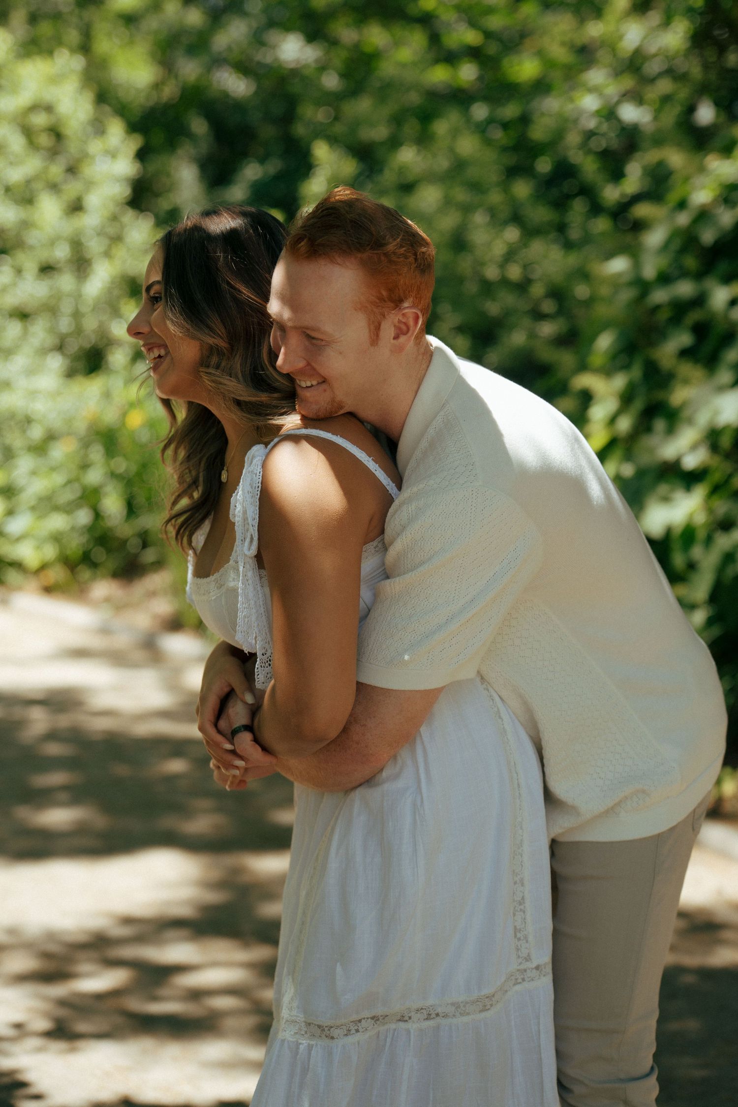 A romantic couple sharing playful moments in a sunlit outdoor setting.