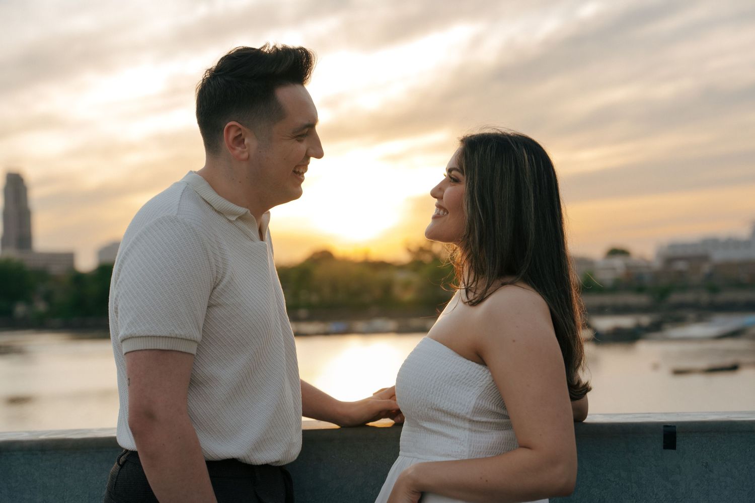 Tender embrace captured during golden hour with water and city views.