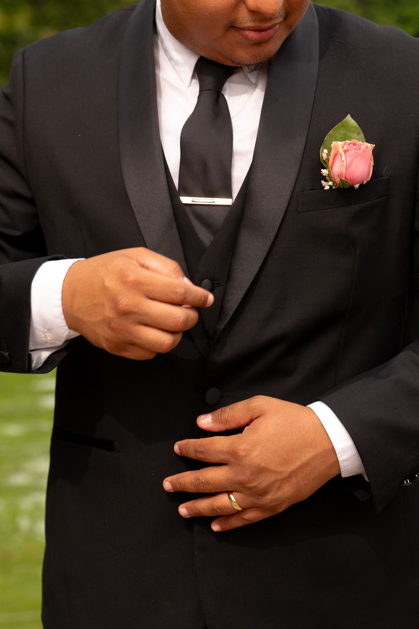 Detail shots of groom adjusting formal black tuxedo and boutonniere.