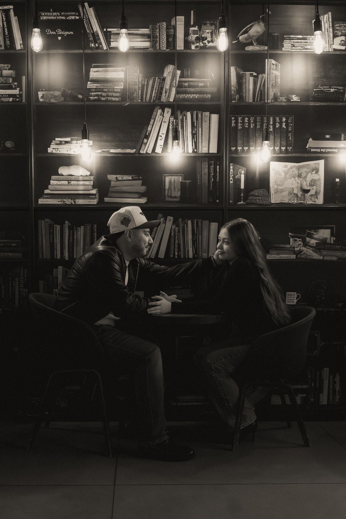 Cozy conversation in moody library setting with illuminated bookshelves creating ambient lighting.