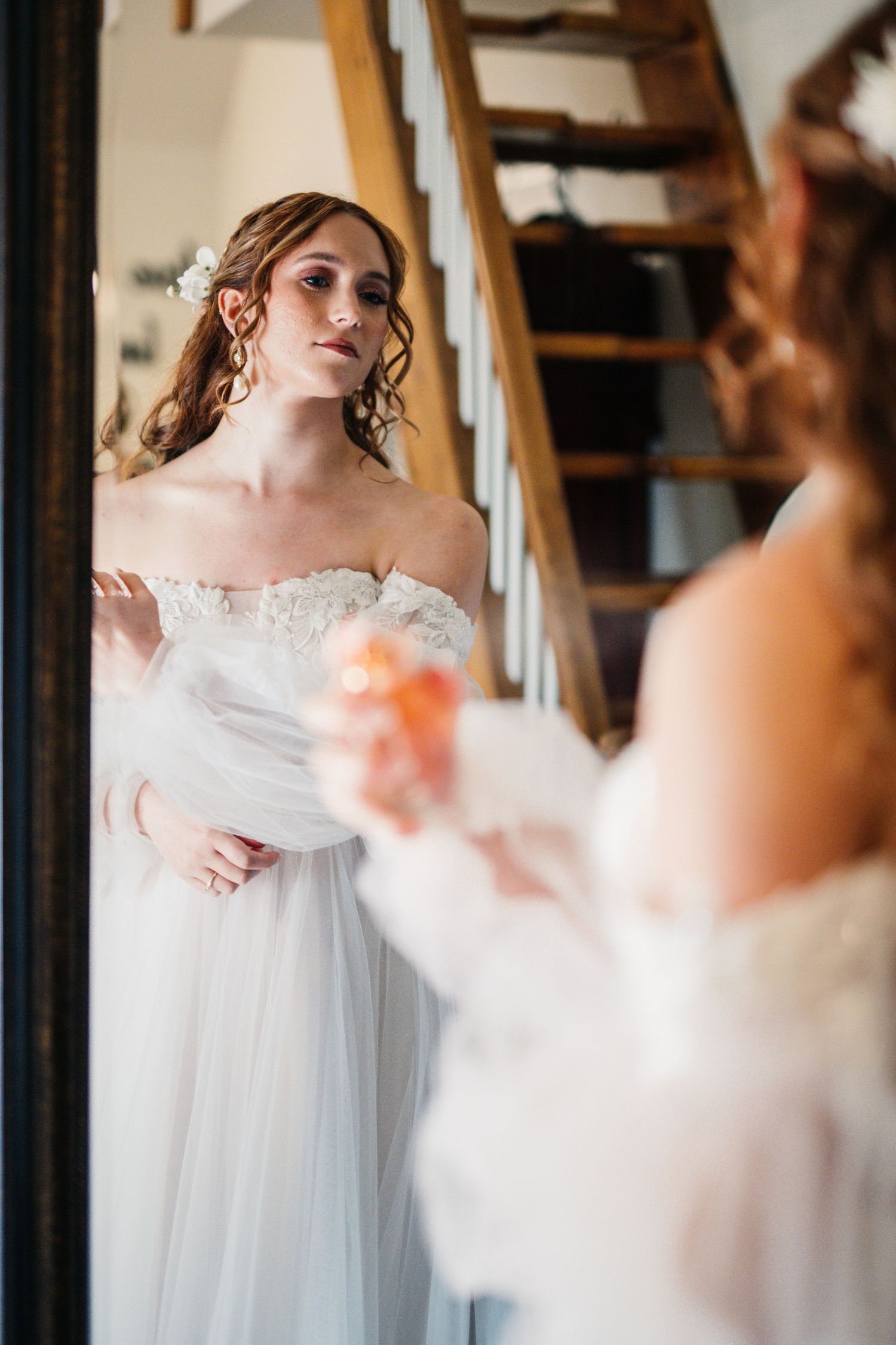 Reflection of someone wearing a white wedding dress in a mirror.
