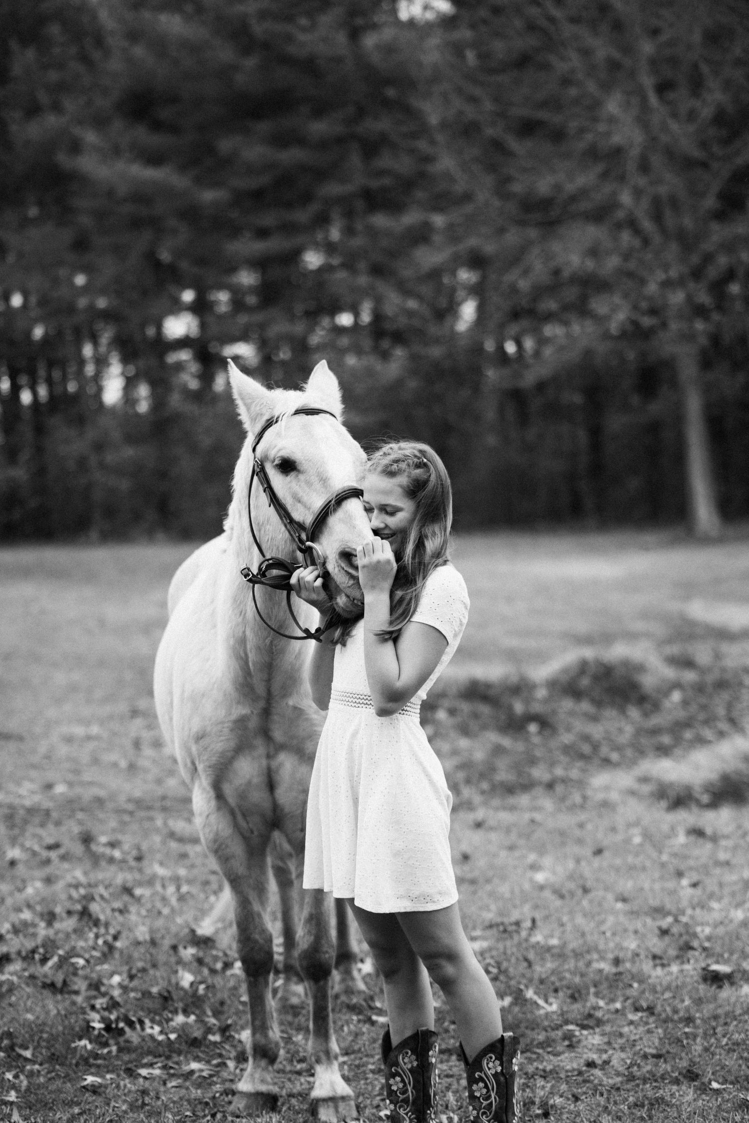 Black and white photo of a white horse and person sharing an intimate moment.