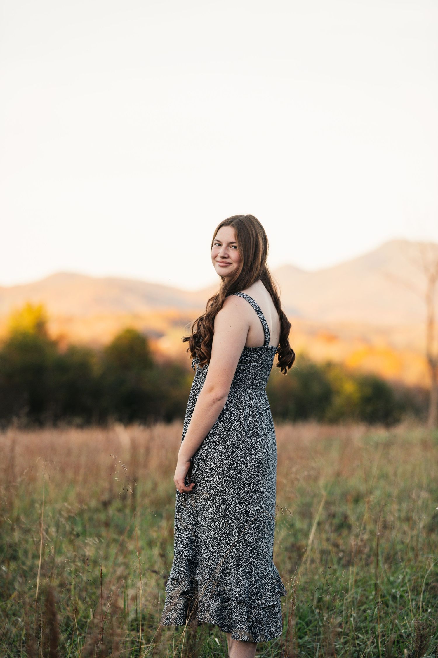 A sunset portrait session in a golden field with mountains in the background.