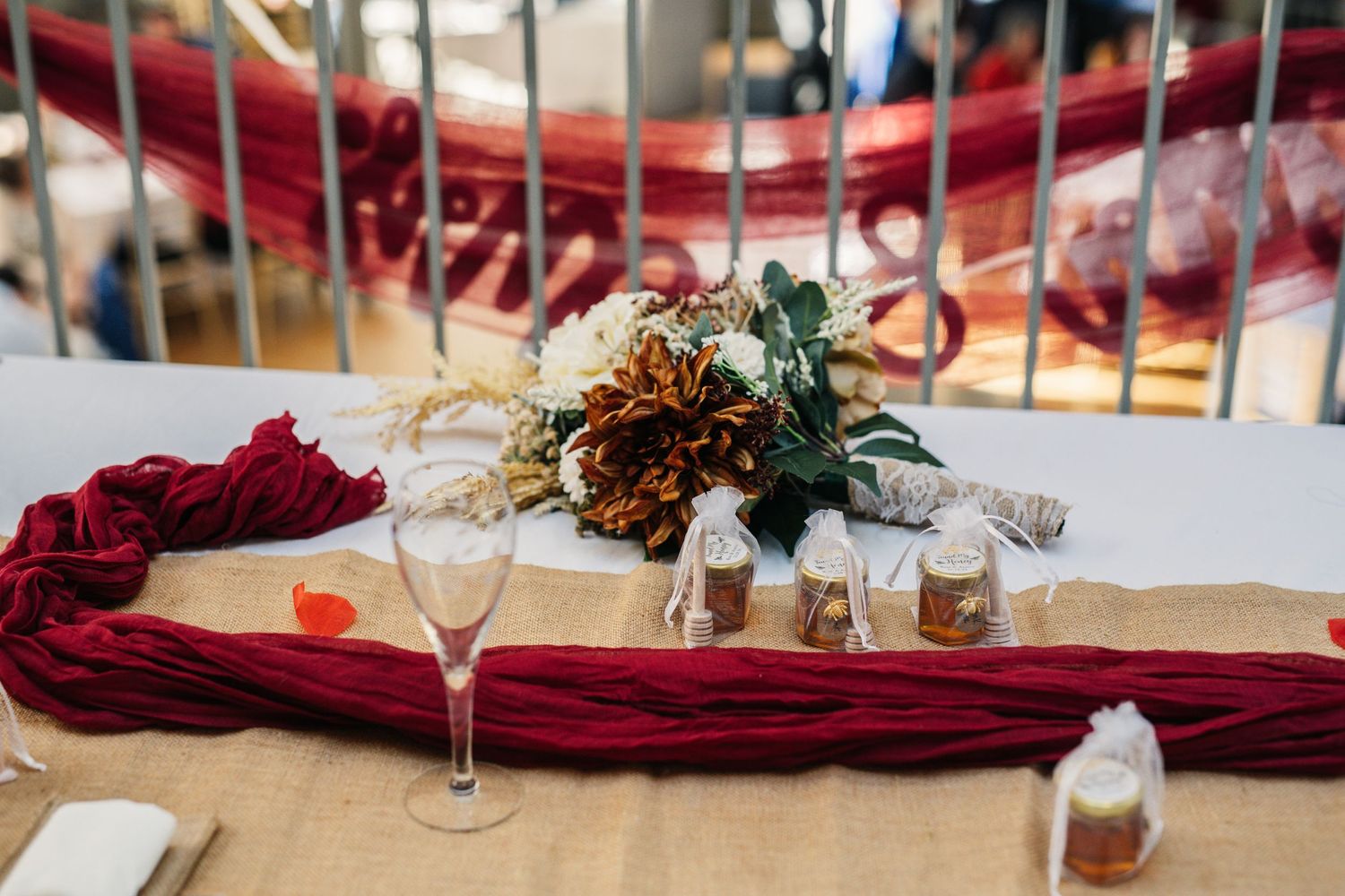 Wedding table setting with burgundy runner and floral centerpiece featuring fall colors.