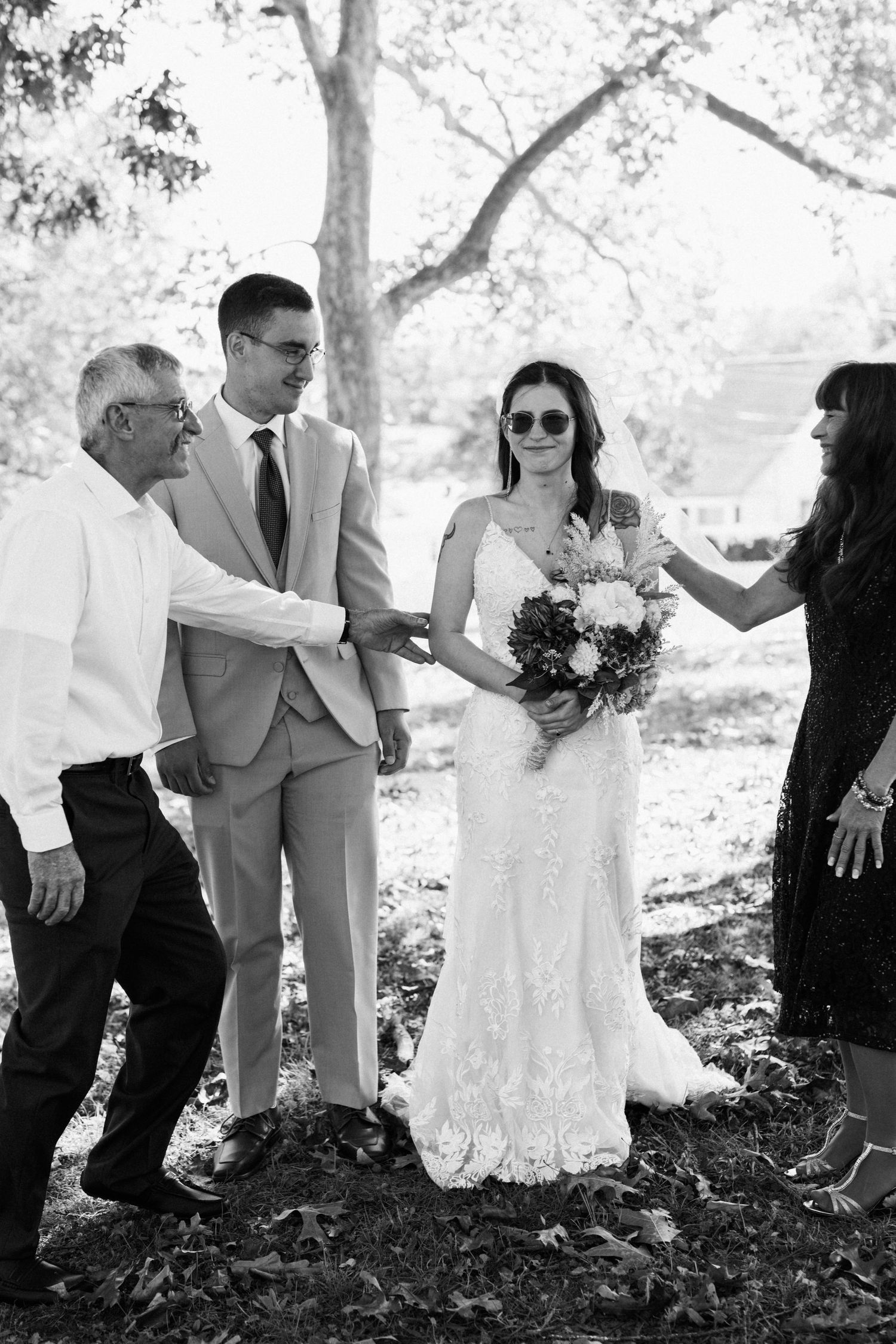 A candid moment captured during a wedding ceremony outdoors under tall trees.