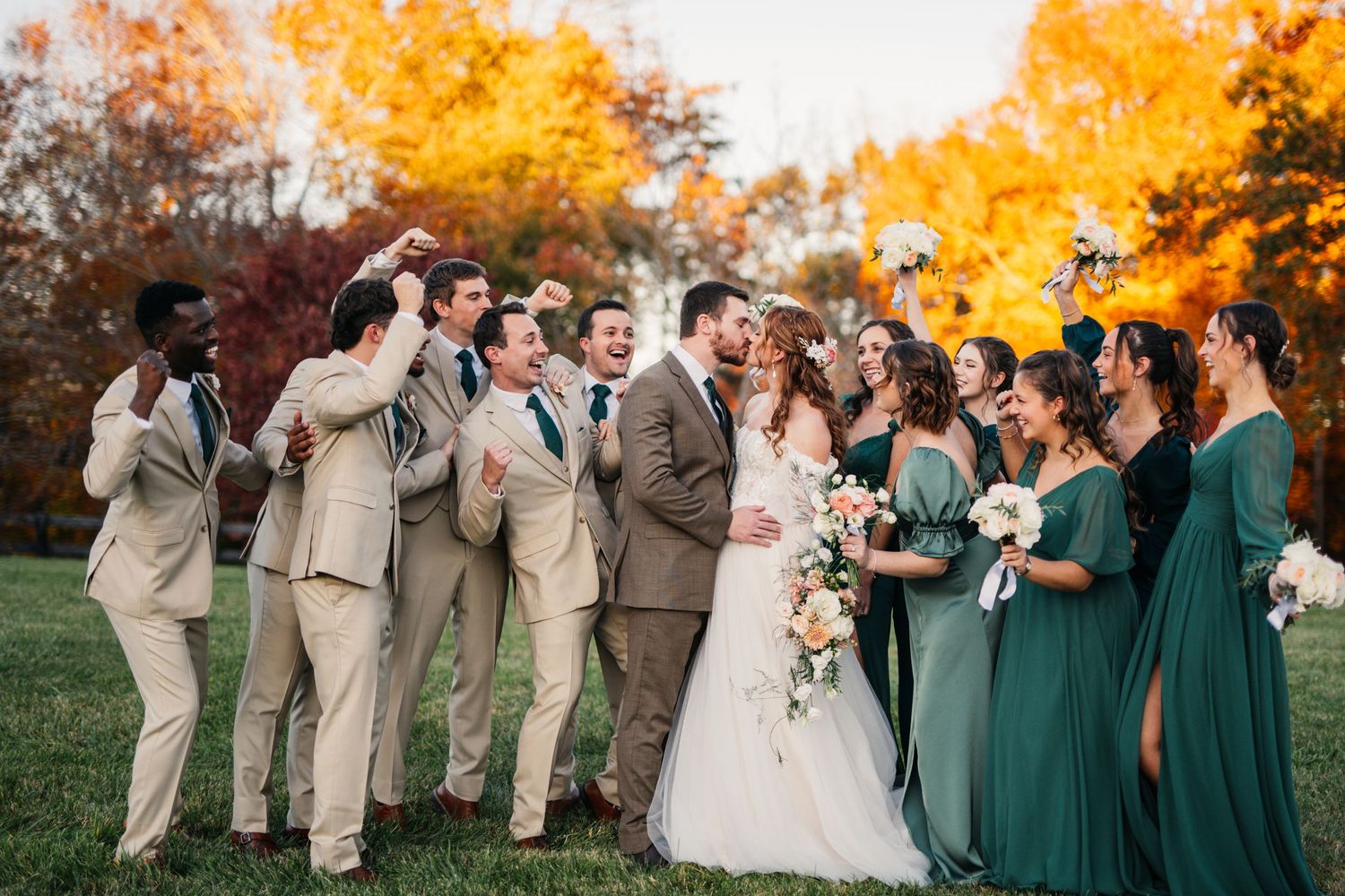Candid wedding party photo with bridesmaids in emerald and groomsmen in beige.