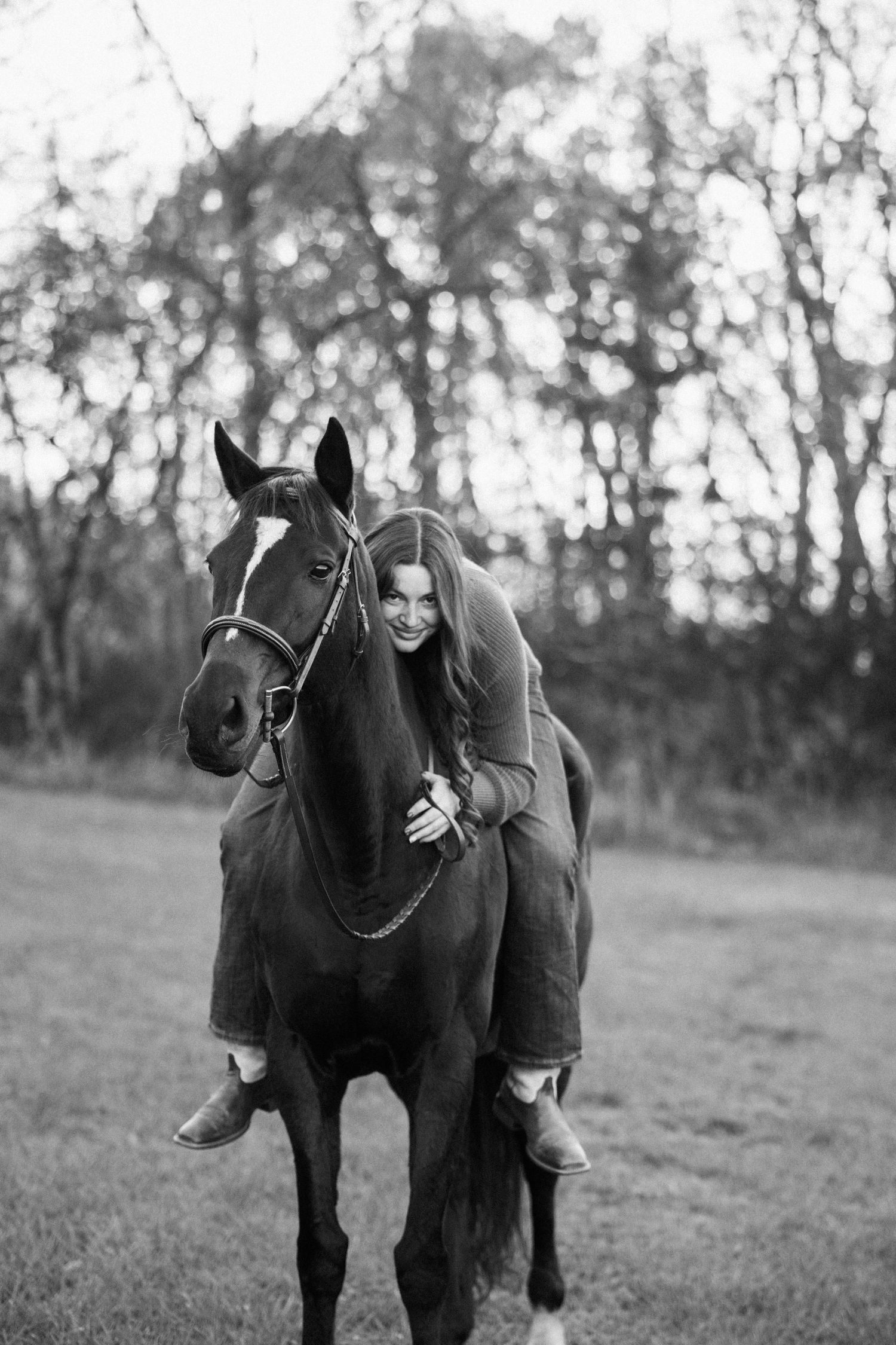 A dark horse with bridle being ridden in a black and white photograph.