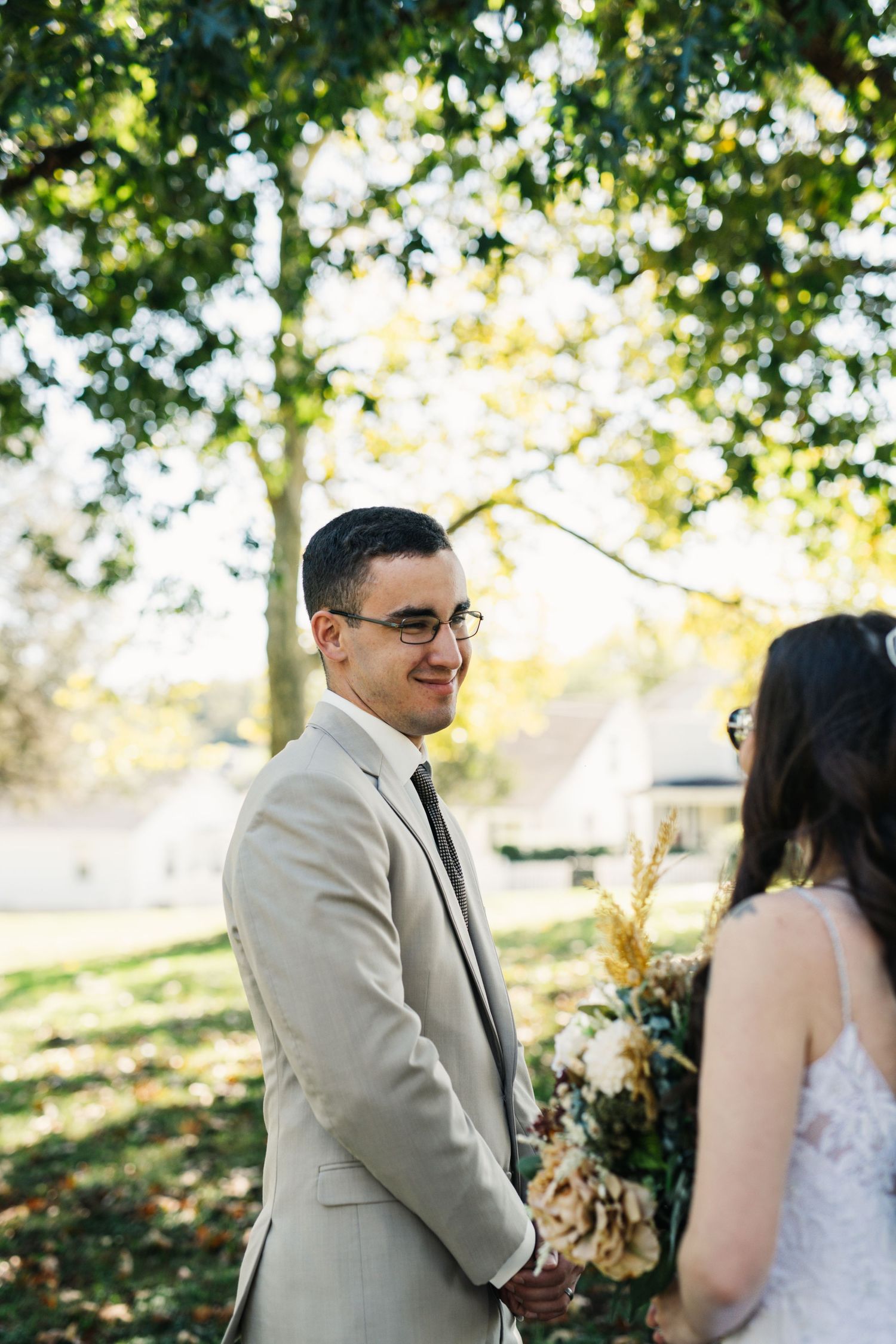 A couple stands together under autumn trees during their wedding ceremony.