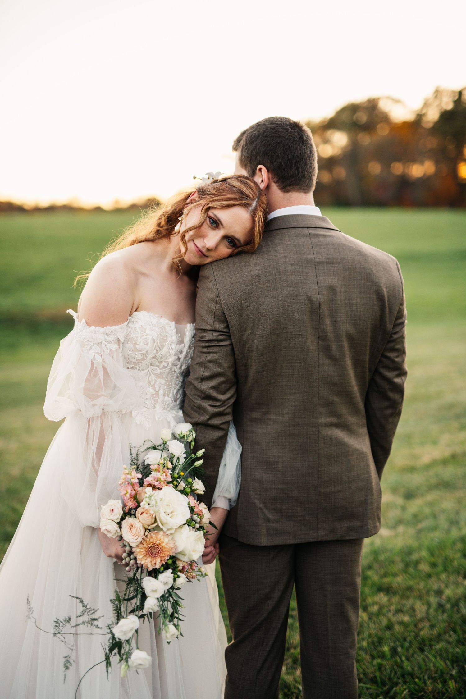 Intimate moment between newlyweds in autumn field at sunset.