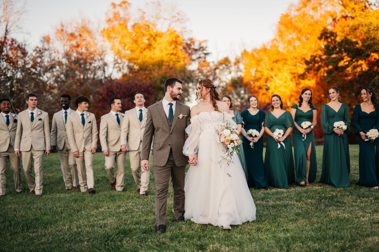 Wedding party lined up outdoors with vibrant fall colors in the background.