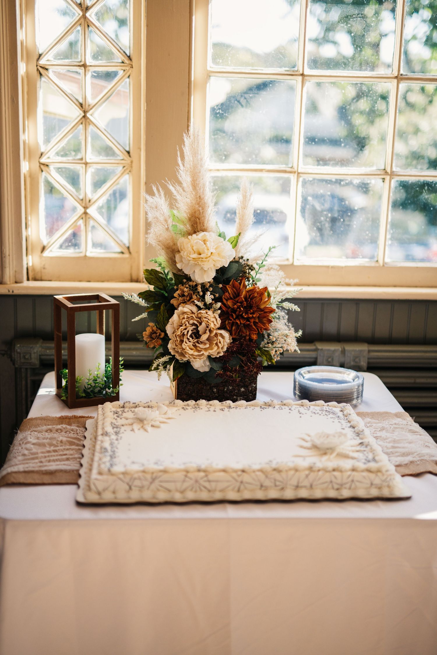 Elegant wedding table decor with floral centerpiece and candles by a window.