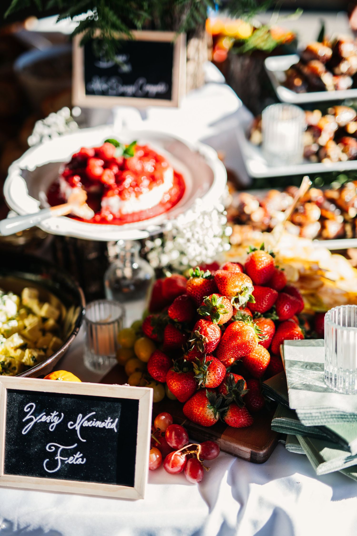 Wedding reception food table with fresh strawberries and elegant place cards.