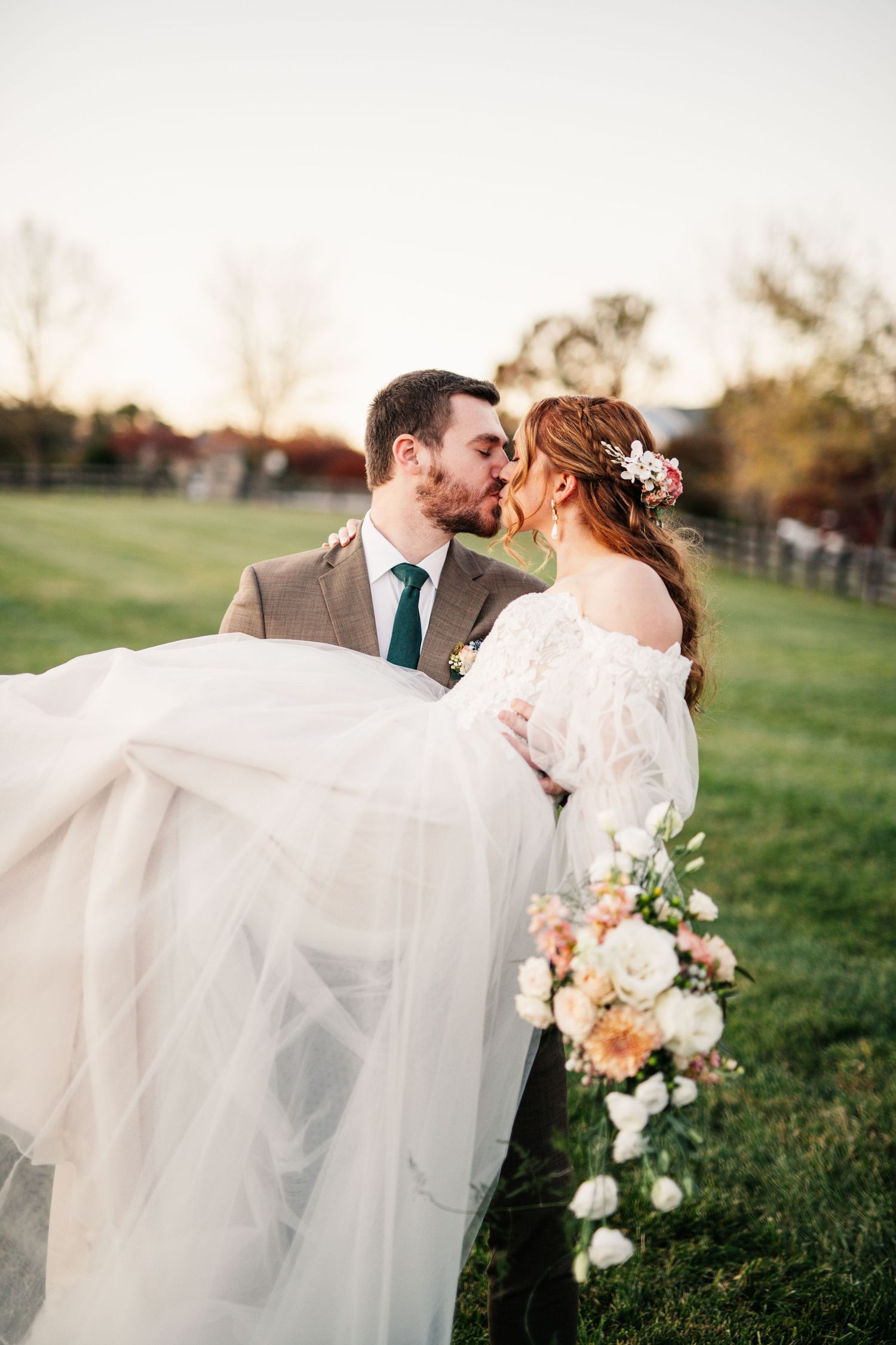 Romantic wedding portrait with flowing veil in evening light.