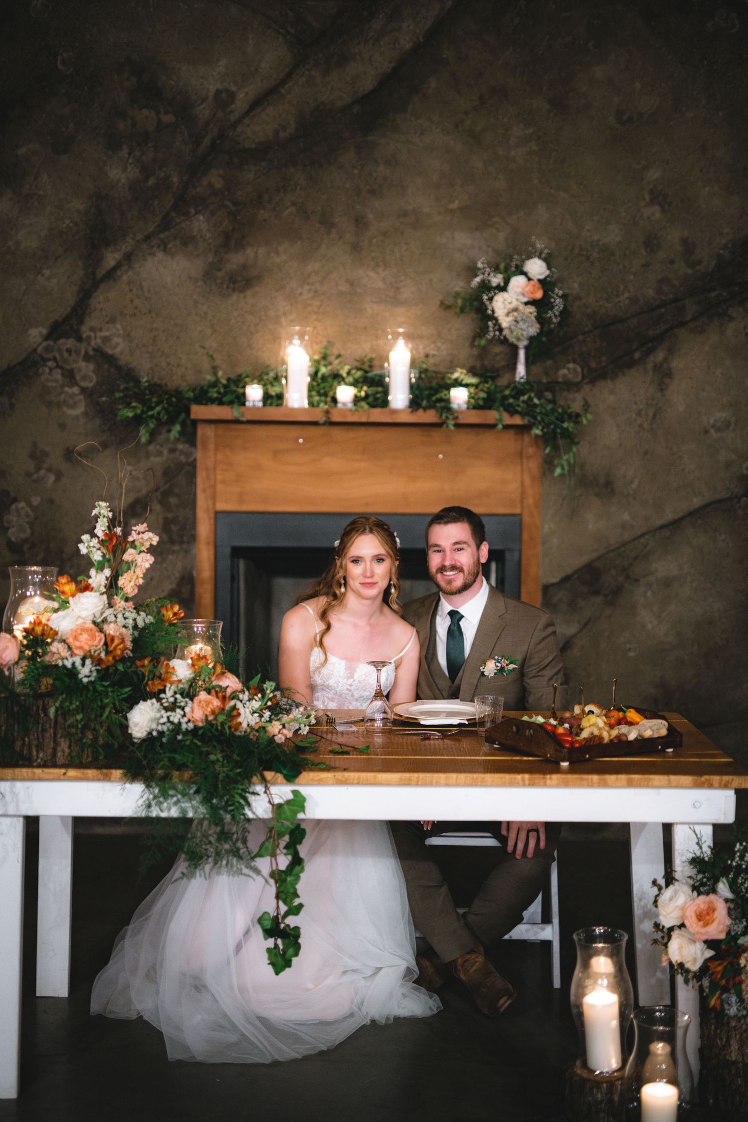 Candlelit rustic wedding reception table decorated with greenery and flowers featuring elegant place settings and lanterns.