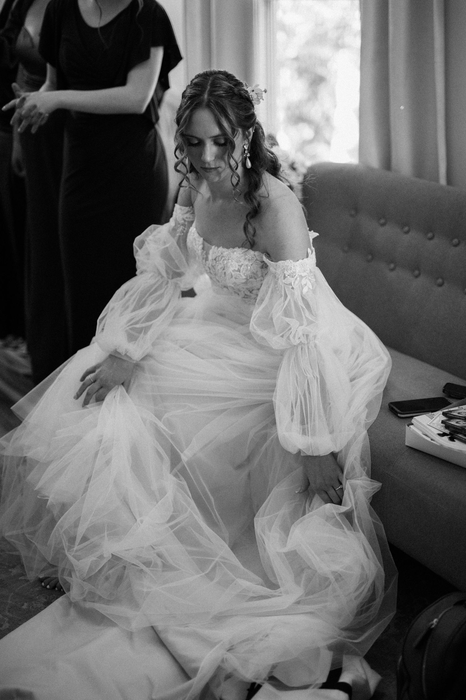 Black and white portrait of someone in an elegant wedding gown with dramatic sleeves.