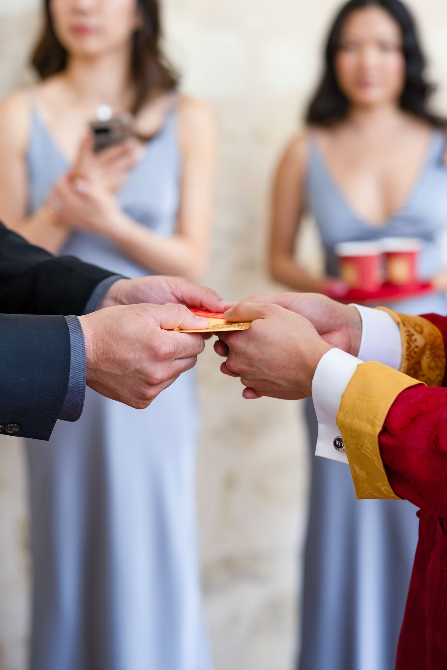 Close-up of hands exchanging a red envelope during a traditional wedding ceremony.
