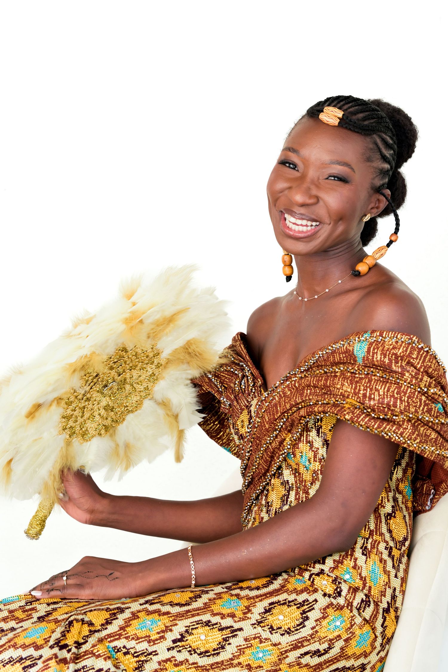 Person in vibrant African print dress posing with yellow paper flower decorations.
