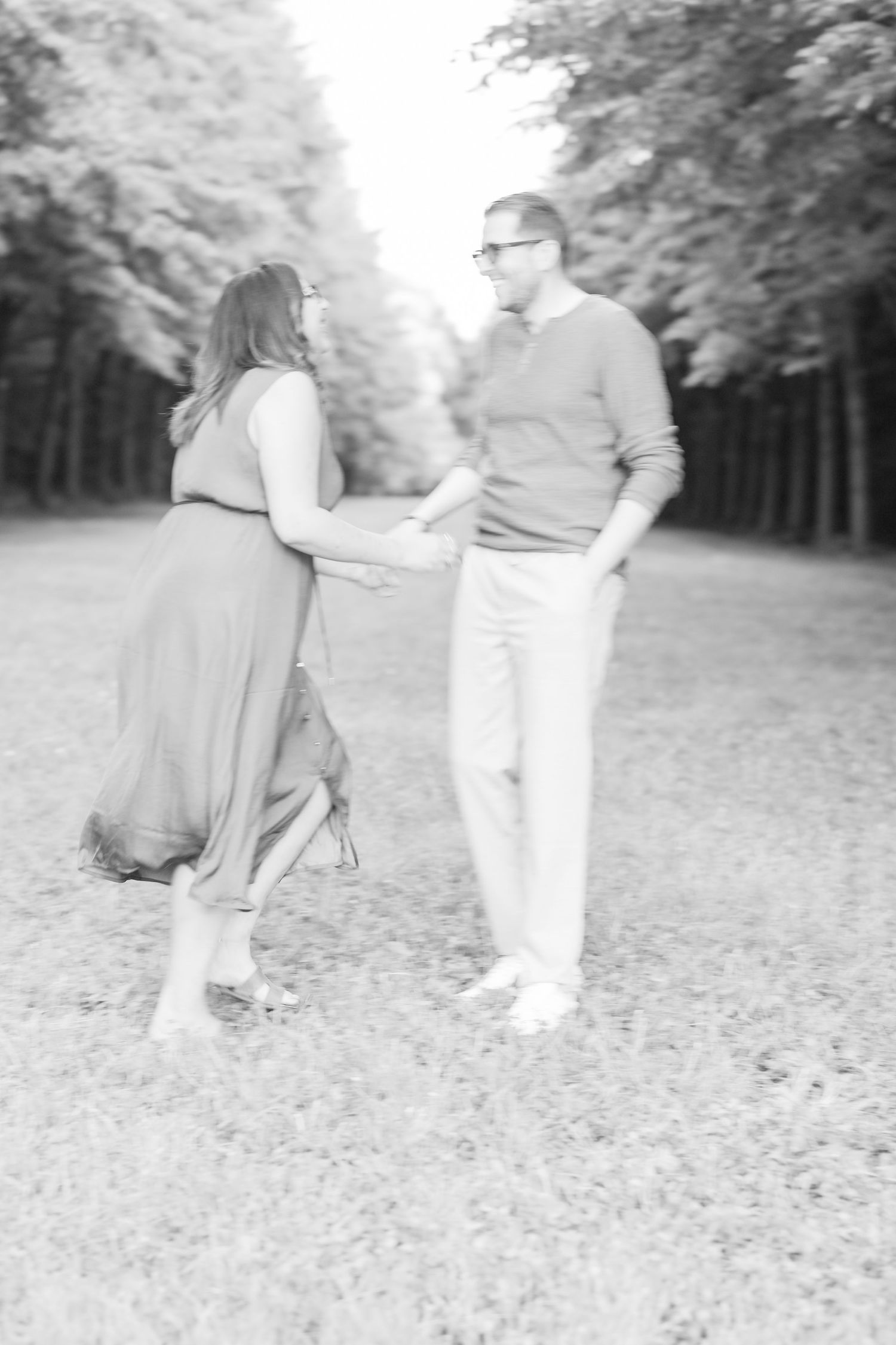 A couple shares a playful moment together on a tree-lined path.