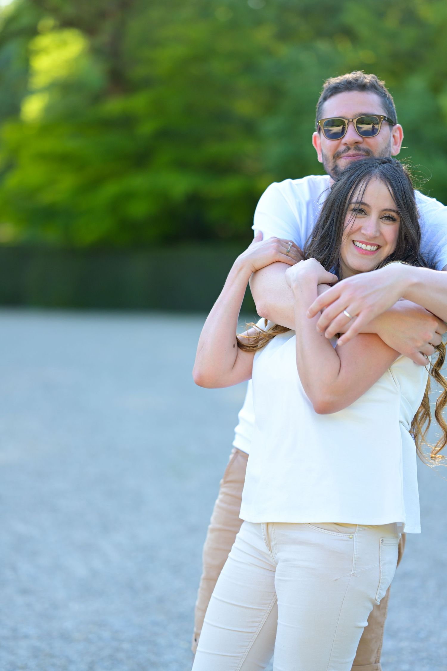 Candid moments captured in white and beige outfits against lush green background.