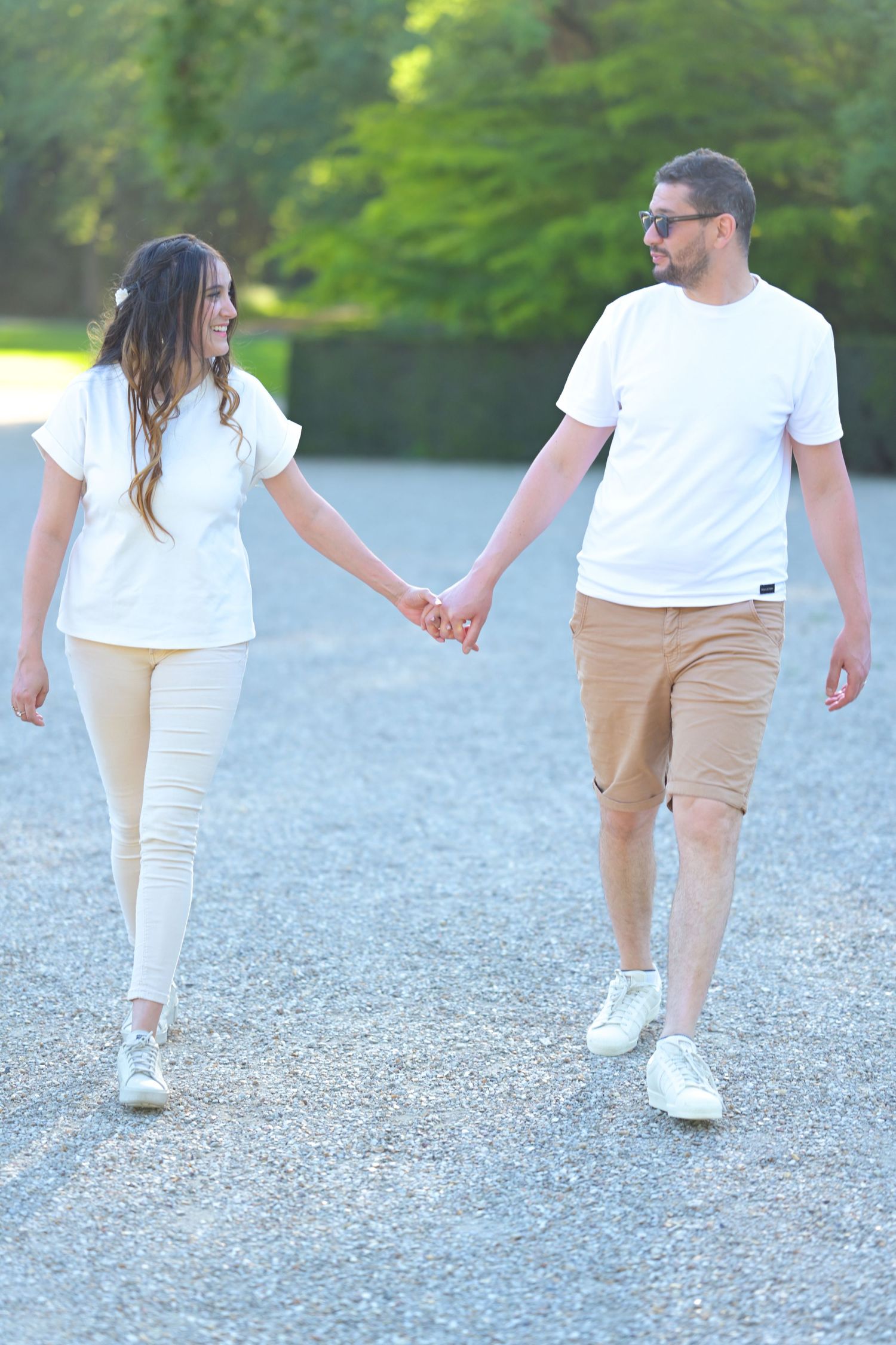 People walking together on a gravel path wearing coordinated white and beige outfits.