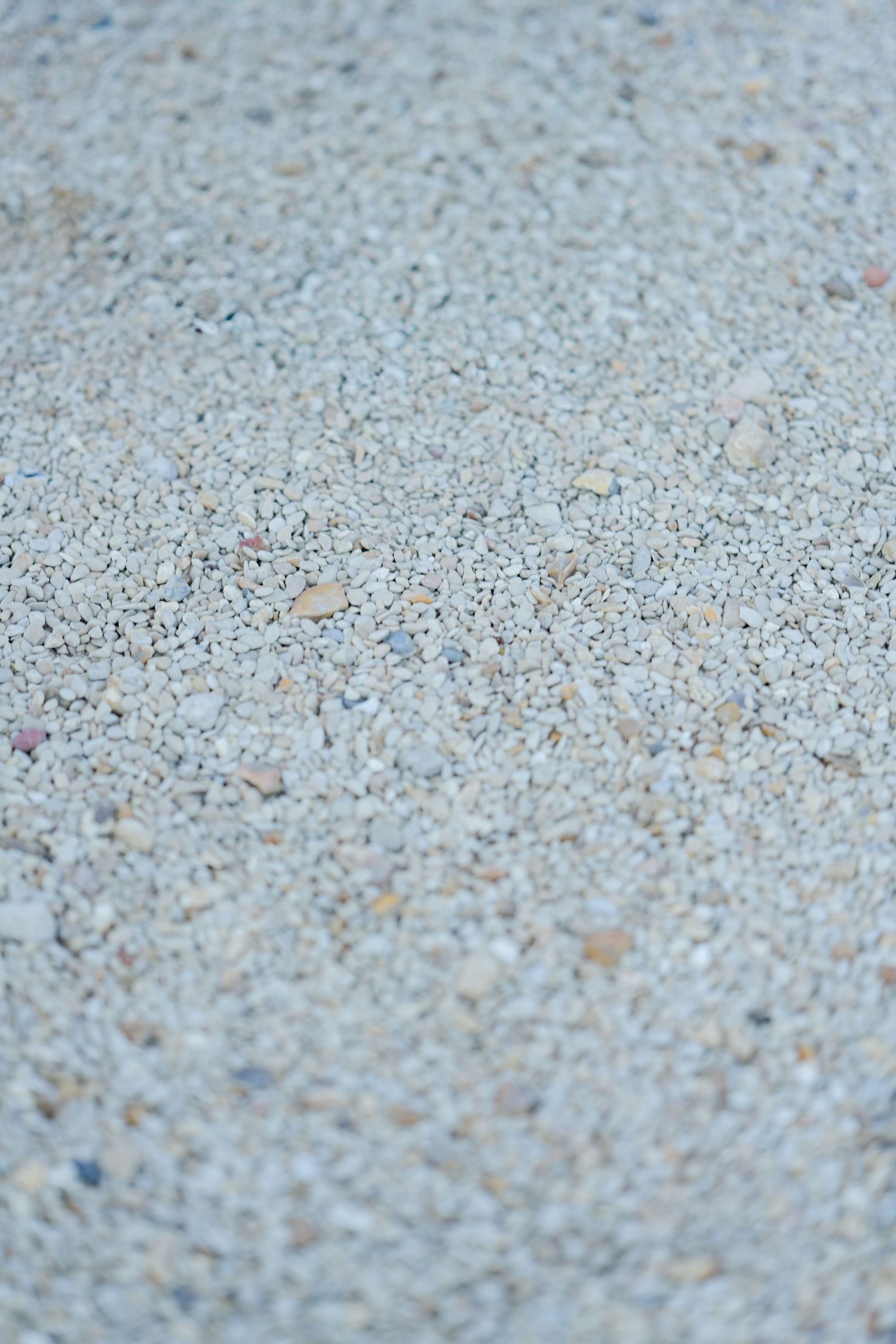 Close-up texture of light colored gravel or crushed stone surface.
