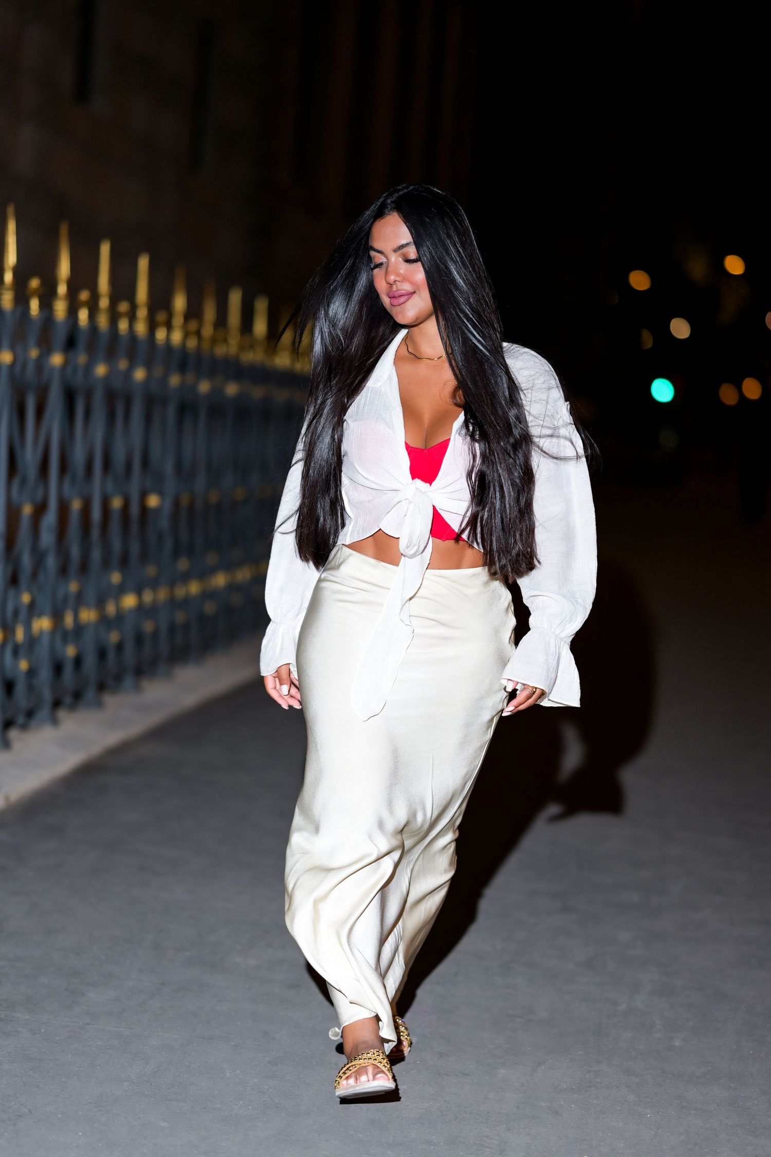 A stylish street fashion photo showing a white crop top and pants ensemble at night.