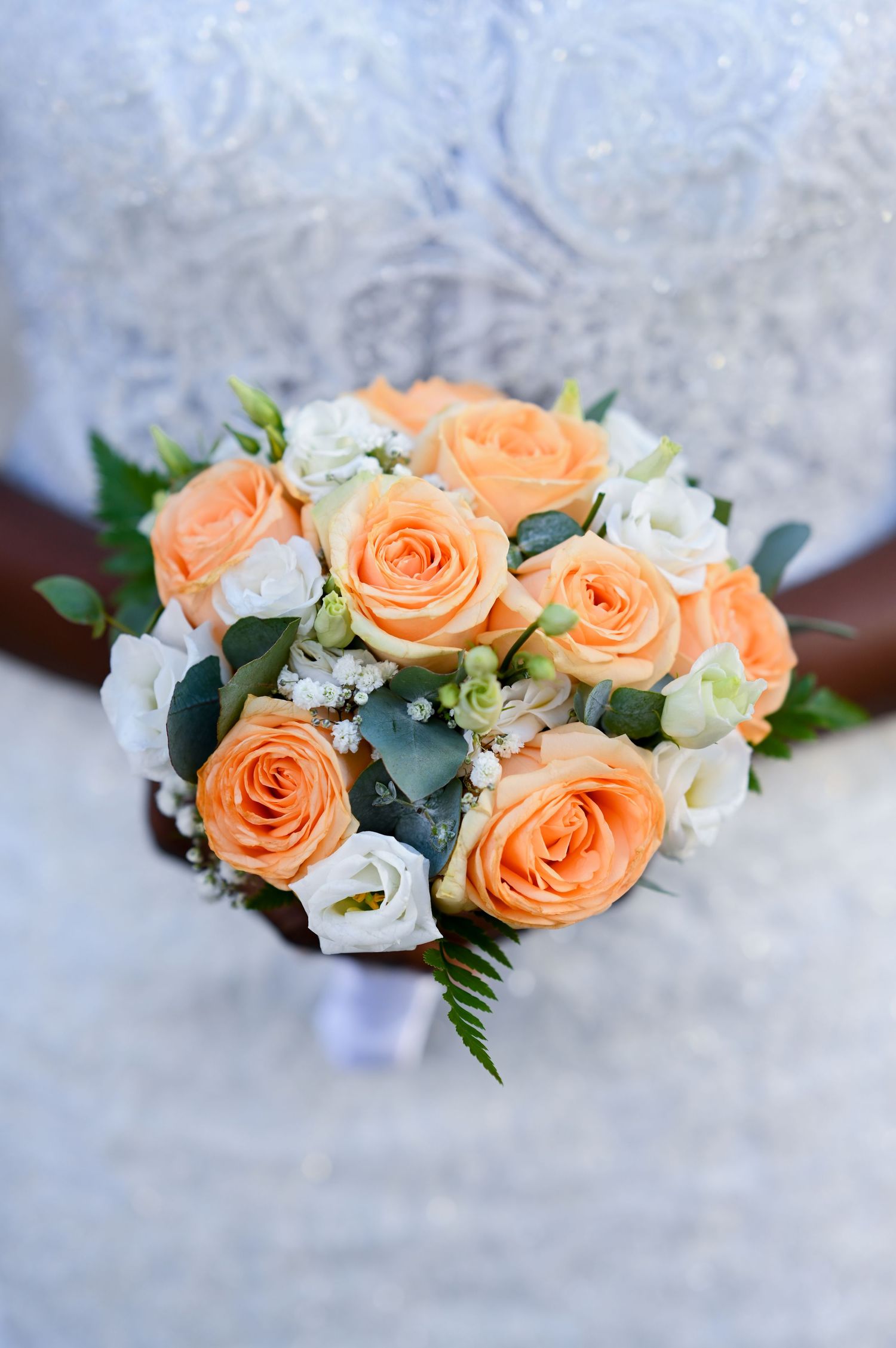 Beautiful peach and white rose bouquet with greenery against a textured background.
