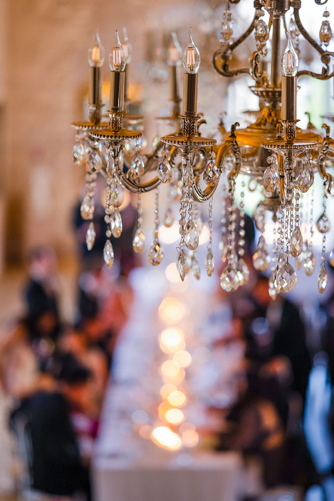 Crystal chandeliers sparkle above a formal dining setting at an elegant reception.