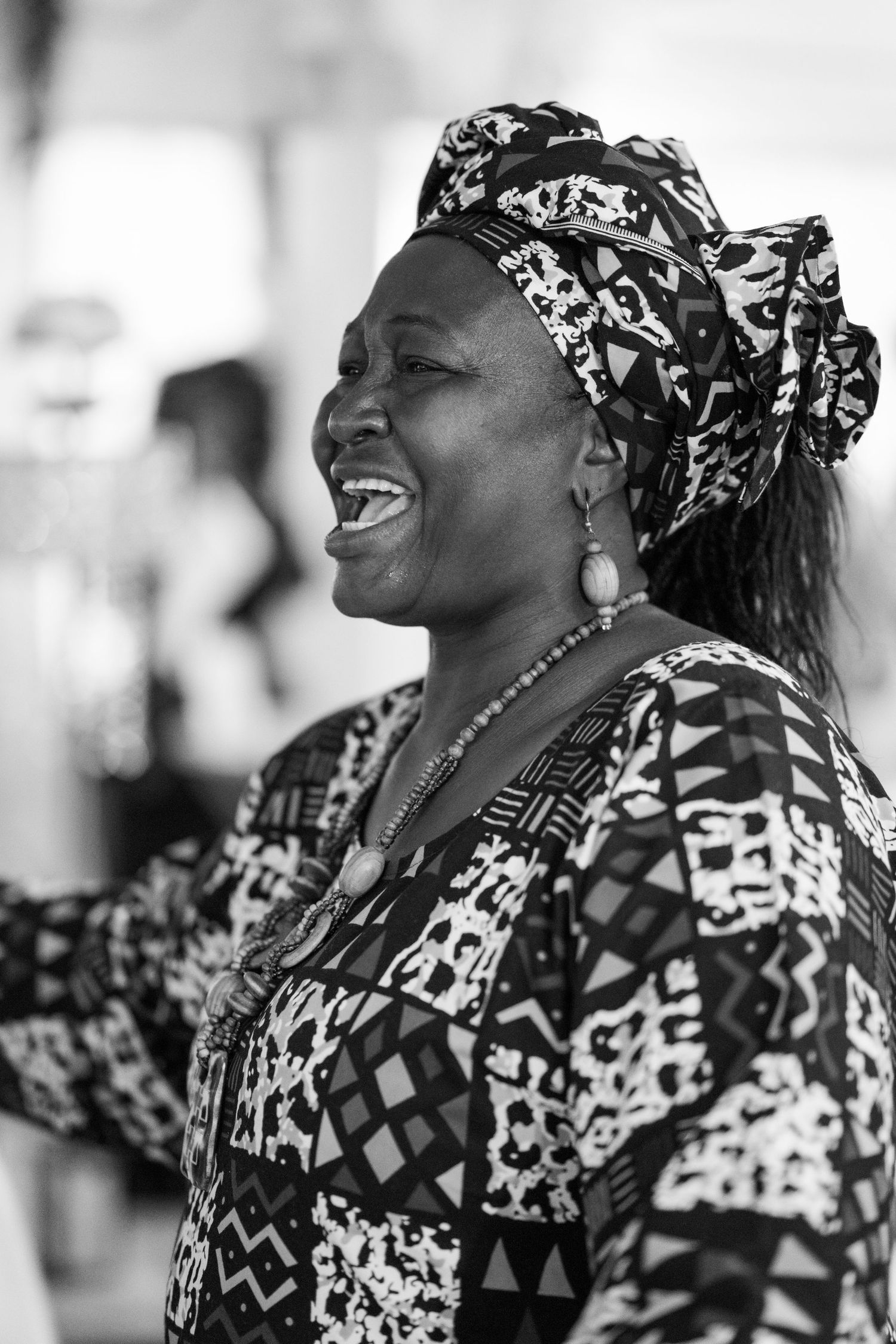 Women in traditional African print headwraps and clothing laughing joyfully during a celebration.